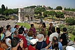 Touristengruppe im Kolosseum mit Konstantinbogen im Hintergrund